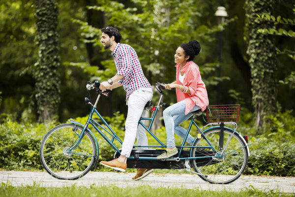 Young couple riding on the tandem bicycle