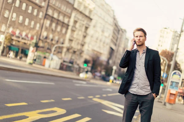 Młody człowiek na ulicy z telefonem komórkowym — Zdjęcie stockowe