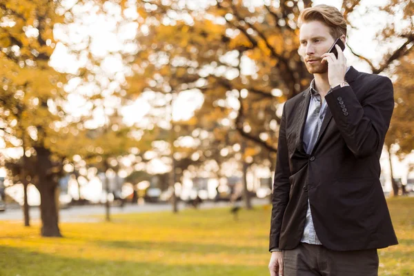 Giovane con cellulare nel parco autunnale — Foto Stock