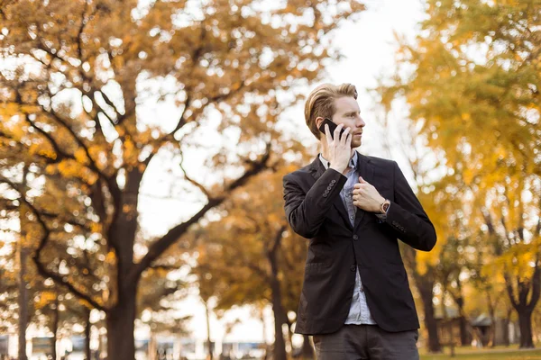 Junger Mann mit Handy im Herbstpark — Stockfoto
