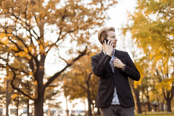 Ung man med mobiltelefon i höstparken — Stockfoto