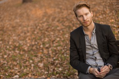 Kürsüye sonbahar Park, genç adam