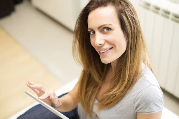 Mujer joven con tableta en casa — Foto de Stock