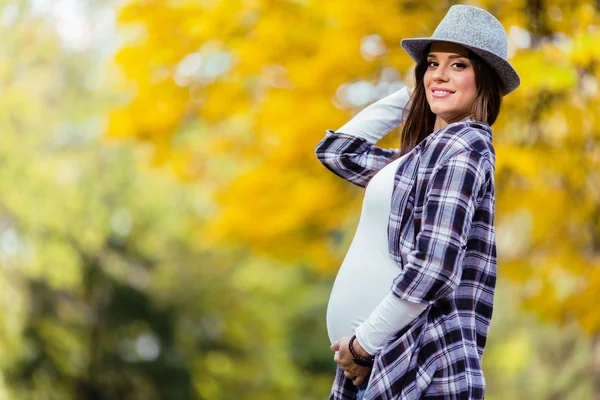 年轻孕妇在秋天的公园 — 图库照片