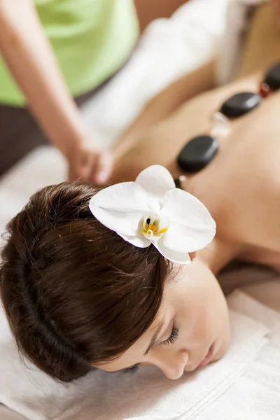 Ung kvinna med en massage med varma stenar terapi — Stockfoto