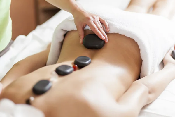 Jonge vrouw met een hot stone-massagetherapie — Stockfoto