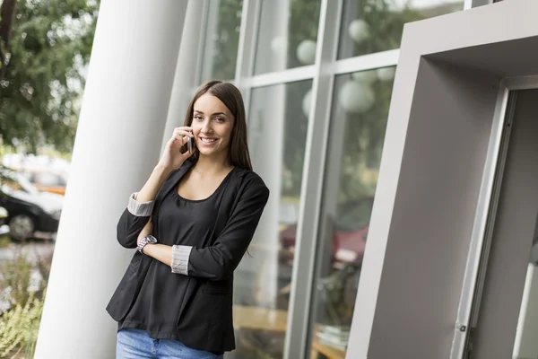 사무실 앞에서 전화 통화를 하는 젊은 여자 — 스톡 사진
