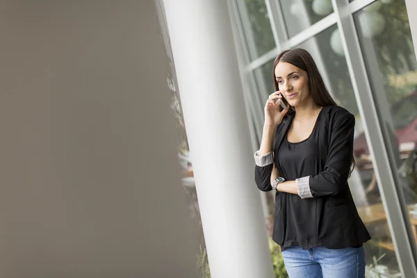 Jeune femme parlant au téléphone devant le bureau — Photo