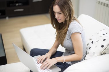 Dizüstü bilgisayarda çalışan genç bir kadın.