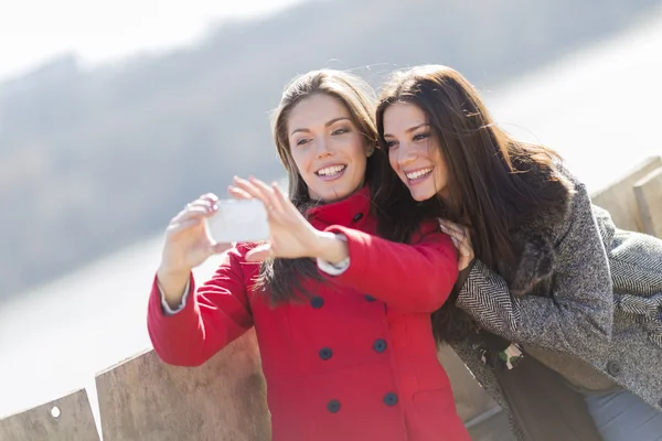 Mujeres jóvenes felices tomando fotos con teléfono móvil — Foto de Stock