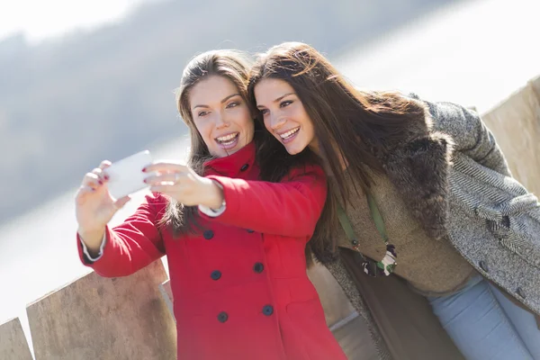 Mujeres jóvenes felices tomando fotos con teléfono móvil — Foto de Stock