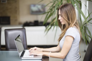 Dizüstü bilgisayarda çalışan genç bir kadın.