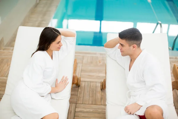 Jovem casal relaxante à beira da piscina — Fotografia de Stock