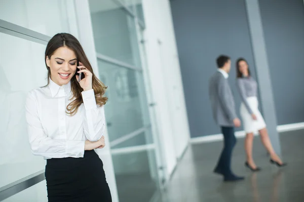Young woman in office with mobile phone — Stock Photo, Image