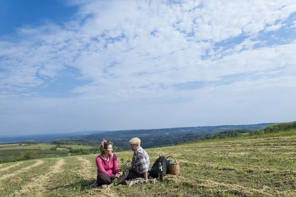 Старшая пара, сидящая в поле — стоковое фото