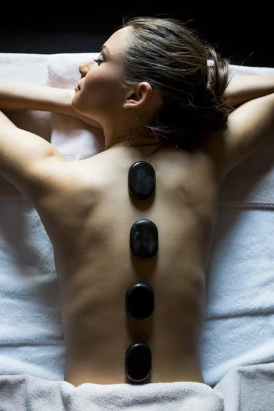 Jonge vrouw met een hot stone-massagetherapie — Stockfoto