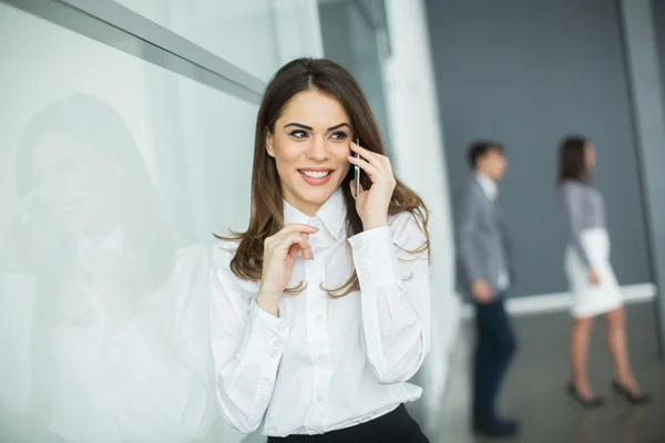 Jeune femme au bureau avec téléphone portable — Photo