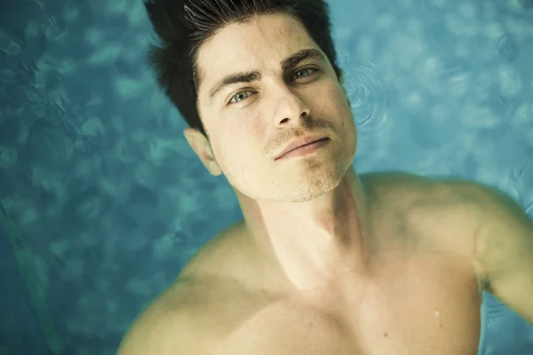 Uima-altaassa kelluva nuori mies — kuvapankkivalokuva