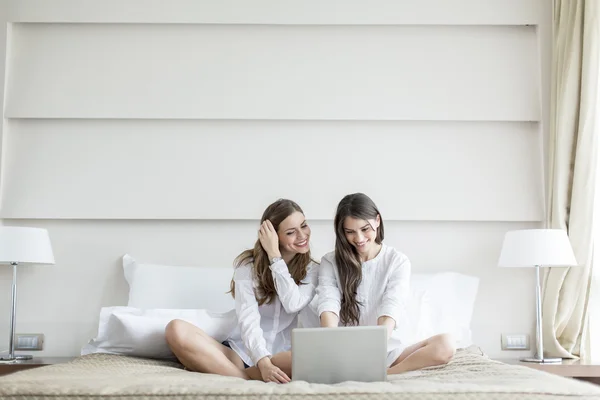 Donne nel letto con il computer portatile — Foto Stock