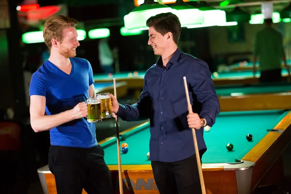 Young men playing pool and drinking beer Stock Photo