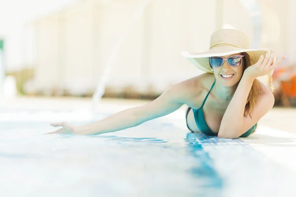Jeune femme posée au bord de la piscine — Photo