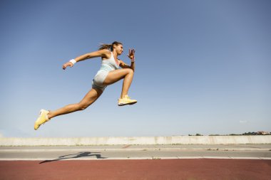 Young woman taking long jump clipart