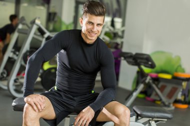 Genç adam spor salonunda antrenman yapıyor.