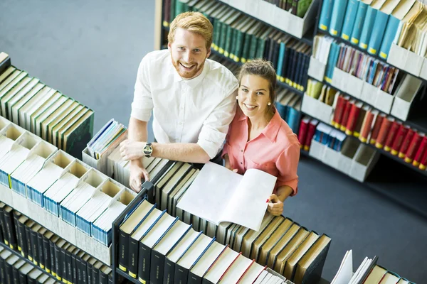 Jeune femme et homme à la bibliothèque — Photo
