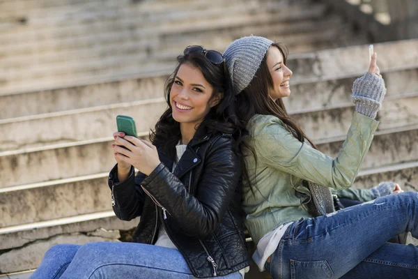 Mujeres jóvenes sentadas en las escaleras con teléfonos móviles — Foto de Stock