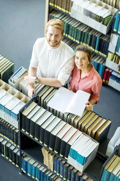 Jeune femme et homme à la bibliothèque — Photo