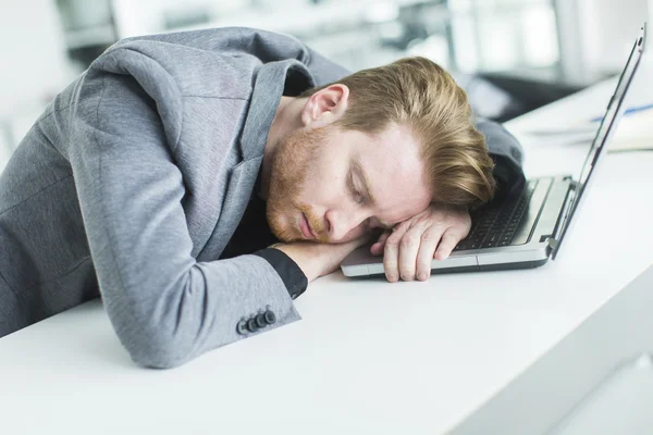 Zmęczony młody człowiek śpi w biurze — Zdjęcie stockowe