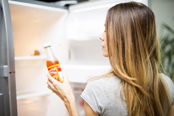Jovem mulher junto ao frigorífico — Fotografia de Stock