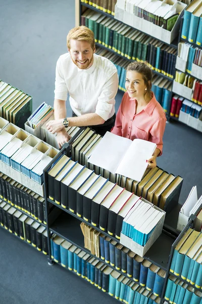 Jeune femme et homme à la bibliothèque — Photo