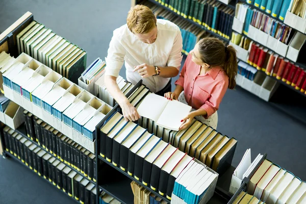 Jeune femme et homme à la bibliothèque — Photo