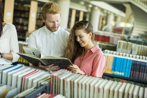 Studenti con libro in biblioteca — Foto Stock