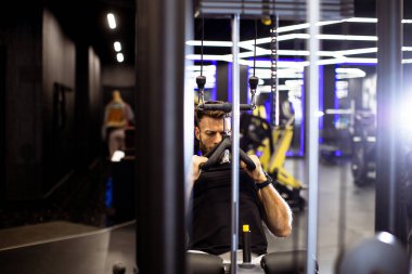 Gelişmiş ekipman ve aydınlatma ile çevrili şık bir spor salonunda güçlü bir antrenman yapıyor..