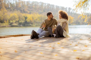 Güneşli bir sonbahar gününde, rengarenk yapraklarla çevrili sakin bir gölün kenarında oturan iki arkadaş birbirlerine eşlik etmekten hoşlanırlar..