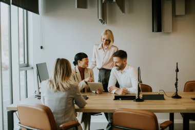 Dört profesyonel masa etrafında dinamik bir tartışma içinde, parlak ofis ortamında fikirleri ve sezgileri paylaşıyorlar..