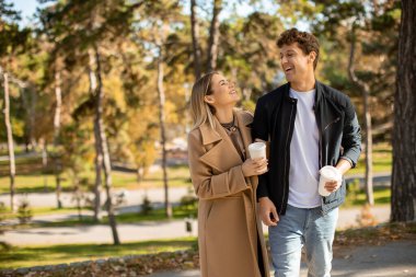 İki insan kıyıda dinlenir, ılık bir içki içerler ve sonbahar güneşinin yumuşak ışığı altında gülümserler.