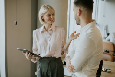İki iş arkadaşı şık bir ofiste dururken dostça bir tartışmaya girişirler. Biri tablet tutarken diğeri dikkatle dinlerken, işbirlikçi bir atmosfer yaratıyor..