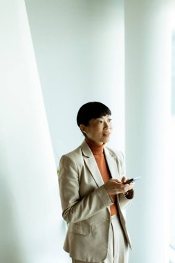 Bir iş adamı parlak bir ofiste elinde kalemle durup düşünceli bir şekilde beyaz bir duvara bakar. Çalışmada iletişim ve profesyonellik üzerinde duruluyor.