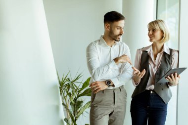 İki profesyonel, doğal ışıkla dolu çağdaş bir ofiste canlı bir tartışmaya giriştiler. Fikirlerini paylaşıyorlar, konuşmalarını geliştirmek için tablet kullanıyorlar..