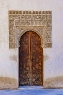Çok güzel detaylandırılmış ahşap bir kapı, ziyaretçileri zengin tarihi ve sanatını keşfetmeye davet eden Alhambra Sarayı 'nın incelikli işçiliğini sergiliyor..