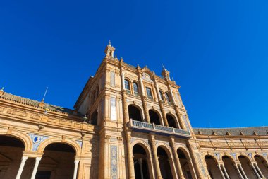 Güneş ışığı, Plaza de Espana 'nın görkemli mimarisini aydınlatır ve ziyaretçileri, İspanya' nın Seville kentindeki karmaşık güzelliğini keşfetmeye davet eder..