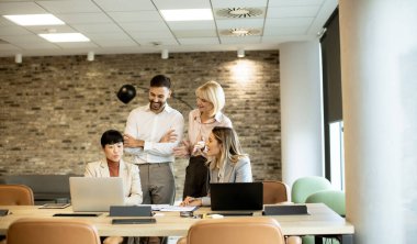 Dört profesyonelden oluşan bir grup, parlak ve çağdaş bir ofiste bir masanın etrafında toplanıyor. Proje detaylarını tartışırken dizüstü bilgisayarlardaki içeriği gözden geçiriyorlar ve fikirleri hevesle paylaşıyorlar..
