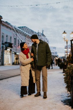 Koreli bir kadın ve beyaz bir erkek, gece boyunca festival ışıklarıyla aydınlatılmış karlı bir sokakta birlikte yürürler. Kış atmosferinin tadını çıkarırken gülüşlerini ve kahkahalarını paylaşıyorlar..