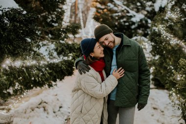 Koreli bir kadın ve beyaz bir erkeğin parıldayan ışıklarla süslenmiş bir kış harikalar diyarında sıcacık kucaklaşmaları gibi sevinç dolu bir an yaşanıyor..