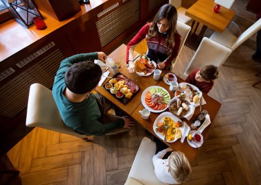 Neşeli bir aile, sıcak bir restoranda toplanır. Renkli tabaklar ve tebessümlerle dolu güzel bir kahvaltıyı paylaşırlar..