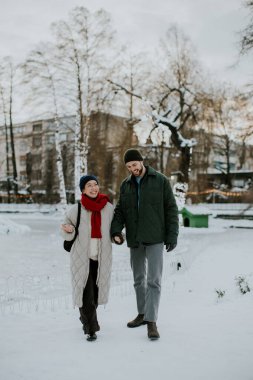 Koreli bir kadın ve beyaz bir adam karlı bir parkta gezintiden zevk alıyorlar. Karla kaplı ağaçlar ve sakin bir kış manzarasıyla el ele tutuşup gülümsüyorlar..