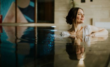 Bir kadın, sakin bir iç mekanda vakit geçirmekten hoşlanır. Suda, usulca gülümsüyor. Uzay, yüzeyine ışık yansıyan modern sanat eserlerine sahiptir..